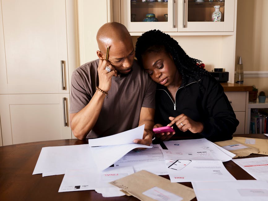 Bankruptcy attorney household-budget review: a calm kitchen-table workspace with a calculator, a household budget worksheet, and a stack of monthly bills neatly organized, the kind of focused review where a bankruptcy attorney walks a household through the means-test math and the realistic options across Chapter 7 and Chapter 13