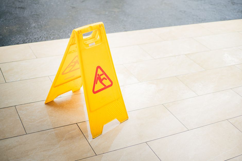 Yellow wet floor caution sign on a tile floor, the kind of hazard warning a slip and fall lawyer examines